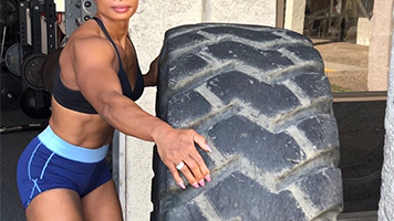 Jennifer Winters rolling a tractor tire during a workout at her gym.